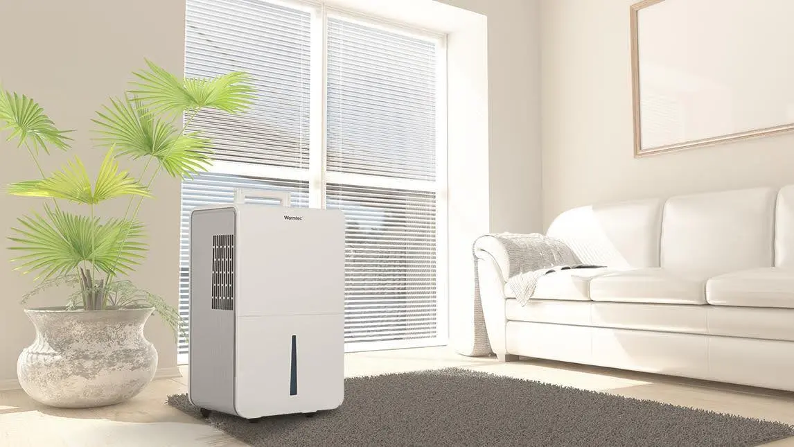 Zdjęcie przedstawia stojący osuszacz powietrza firmy Warmtec ODT-25N w pokoju dziennym.